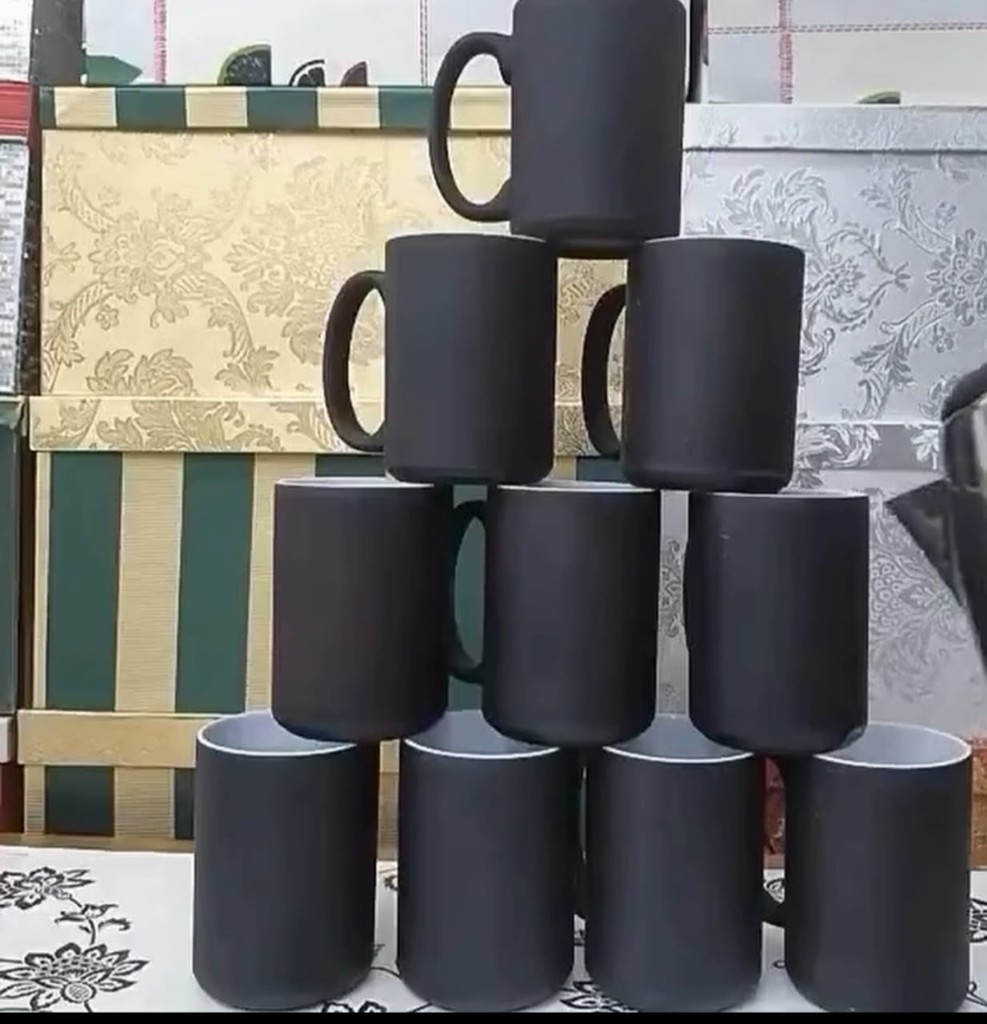 Stack of matte black ceramic mugs with white interiors